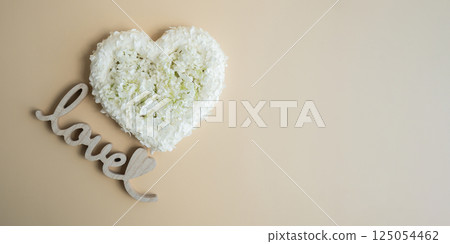 Heart made of white lilac flowers on pastel beige background Wooden word LOVE. Still life romantic composition of Valentines day holiday copy space for your text invitation greeting card Heart made of white lilac flowers on pastel beige background Wooden word LOVE. Still life romantic composition of Valentines day holiday copy space for your text invitation greeting card 125054462