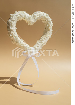 Heart made of white lilac flowers levitating on pastel beige background. Still life romantic composition of Valentines day holiday copy space for your text invitation greeting card 125054474