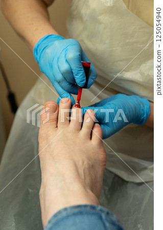 Podiatrist applying red nail polish during final pedicure step Podiatrist applying red nail polish during final pedicure step 125054940