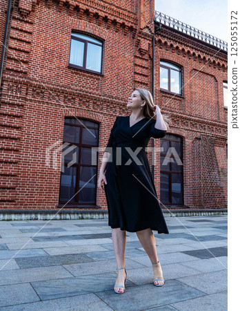 Elegant pregnant woman poses outdoors in a stylish black dress near historic brick buildings at dusk Elegant pregnant woman poses outdoors in a stylish black dress near historic brick buildings at dusk 125055172