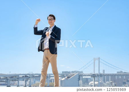A businessman smiling and posing with a fist in the air 125055989
