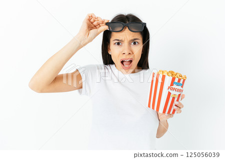 A woman is holding a red and white popcorn bucket and wearing sunglasses 125056039