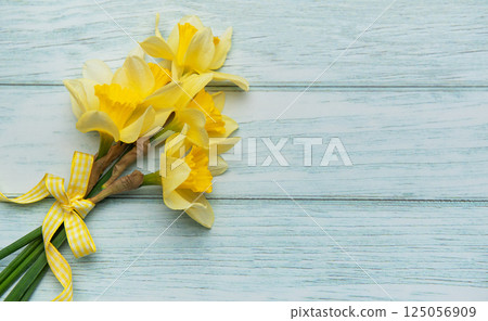Bouquet of yellow daffodils lying on rustic wooden table 125056909
