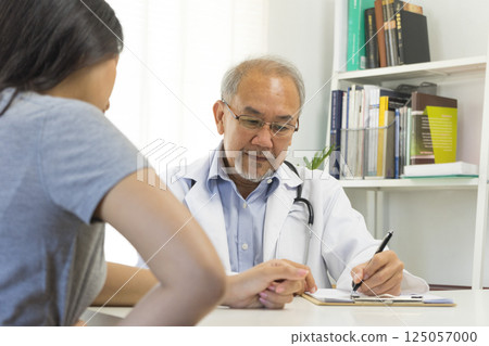 Senior Asian doctor talking with young female patient in hospital. Senior Asian doctor talking with young female patient in hospital. 125057000