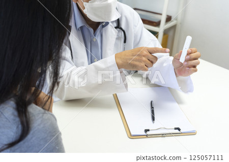 Male doctor show Rapid Antigen Test kit with Negative result to female patient. 125057111
