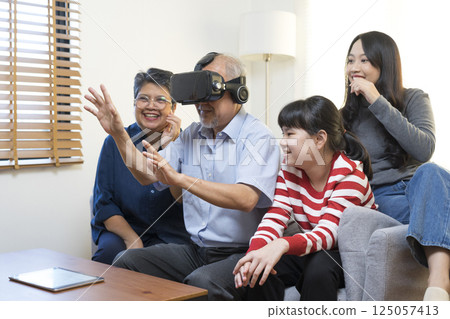Happy Asian family having fun with virtual reality headset VR in living room at home. grandparent try VR technology with grand children. 125057413