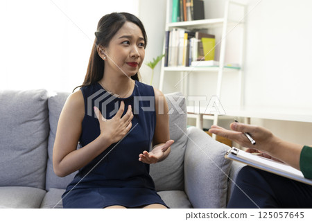 Asian psychologist doctor having session with young depressed woman in clinic. Psychology and mental therapy concept. 125057645