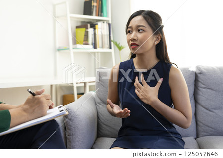 Asian psychologist doctor having session with young depressed woman in clinic. Psychology and mental therapy concept. 125057646