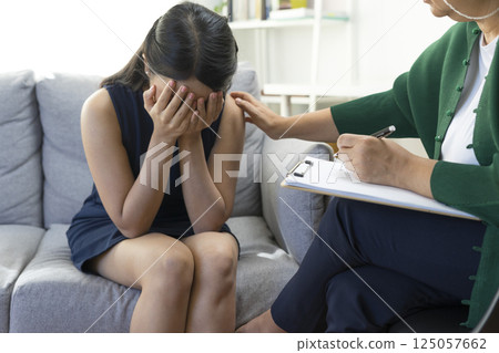 Asian psychologist doctor having session with young depressed woman in clinic. Psychology and mental therapy concept. Asian psychologist doctor having session with young depressed woman in clinic. Psychology and mental therapy concept. 125057662