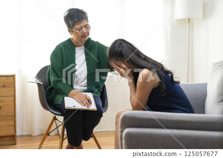 Asian psychologist doctor having session with young depressed woman in clinic. Psychology and mental therapy concept. 125057677