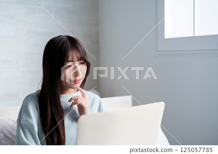 A woman who looks at a computer and thinks 125057785