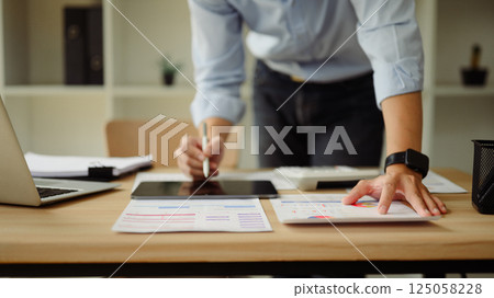 Cropped shot of young businessman working with financial reports and digital tablet 125058228