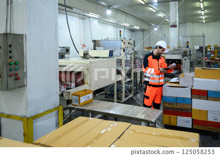 Male worker inspecting canned products in a seafood factory packaging area 125058253