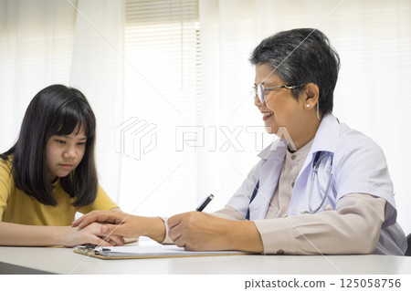Patient writing personal info while listen to the senior doctor. 125058756