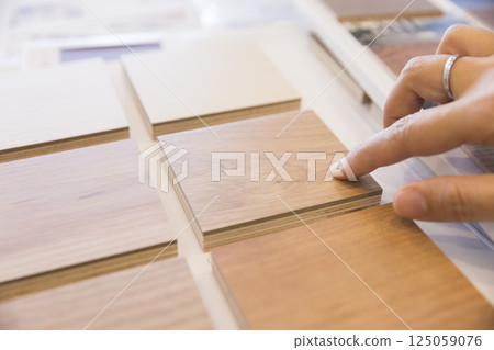 一位女士從地板樣品中選擇顏色 - 房屋建築會議 一位女士從地板樣品中選擇顏色 - 房屋建築會議 125059076