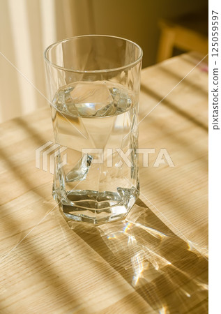 Clear glass of water on wooden table with beautiful sunlight and reflections. High quality photo 125059597