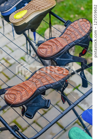 Outdoor sandals drying upside down on metal rack with rubber soles visible. High quality photo 125059602