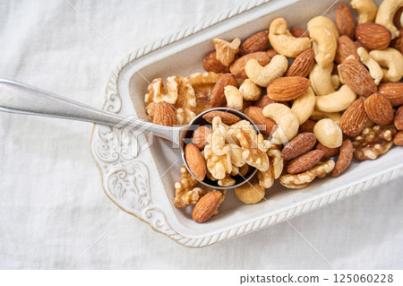 Mixed nuts in a white bowl and spoon 125060228