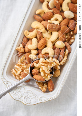 Mixed nuts in a white bowl and spoon 125060232