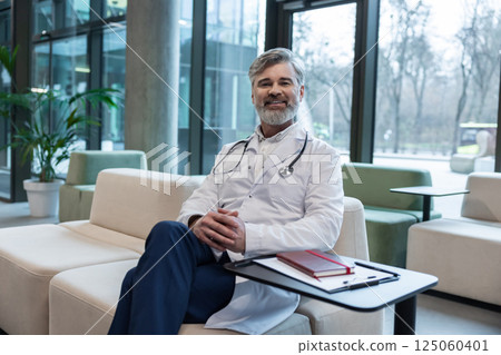 Smiling mature male doctor in lab coat looking positive and contented Smiling mature male doctor in lab coat looking positive and contented 125060401