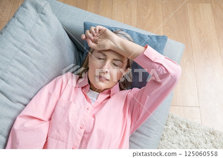 Senior caucasian woman in pink shirt lying on the bed and suffering form the headache Senior caucasian woman in pink shirt lying on the bed and suffering form the headache 125060558