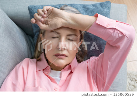 Senior caucasian woman in pink shirt lying on the bed and suffering form the headache Senior caucasian woman in pink shirt lying on the bed and suffering form the headache 125060559