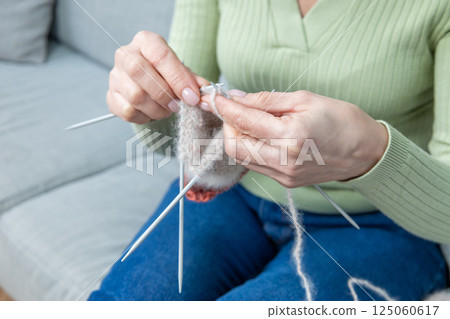 Woman spending time at home and knitting while sitting on the sofa Woman spending time at home and knitting while sitting on the sofa 125060617