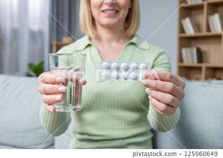 Blonde woman in her 50s taking hormone replacement pills 125060649