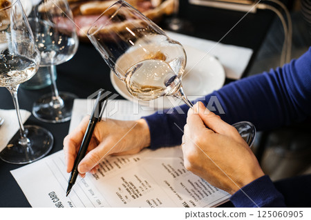 Woman selecting a wine during a wine workshop session at a shared table. Wine workshop, food literacy, decision making, group wine class 125060905