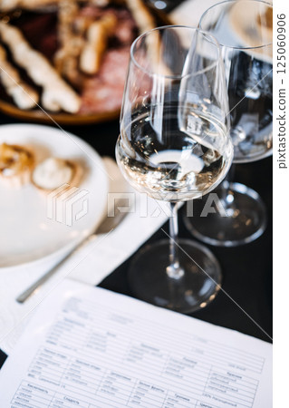 White wine glasses on table with pairing snacks and tasting sheet. Captures modern sommelier culture, sensory branding, and curated lifestyle 125060906