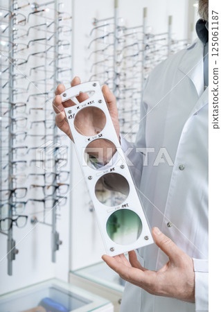 Male doctor in the optic shop holding a lens color scale in hands 125061187