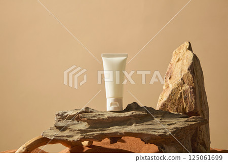 Tube of cream mockup placed on a gnarled tree trunk with many tiny holes and grains. The wooden plank was rotten and next to it was a rough rock. Empty space for showing product or designing. Tube of cream mockup placed on a gnarled tree trunk with many tiny holes and grains. The wooden plank was rotten and next to it was a rough rock. Empty space for showing product or designing. 125061699