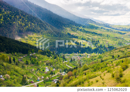 mountainous countryside landscape with synevyr village in the valley. scenic farmland. cloudy weather. rural fields and meadows on the forested slopes of a hill. rolling scenery in spring. lush mountainous countryside landscape with synevyr village in the valley. scenic farmland. cloudy weather. rural fields and meadows on the forested slopes of a hill. rolling scenery in spring. lush 125062020