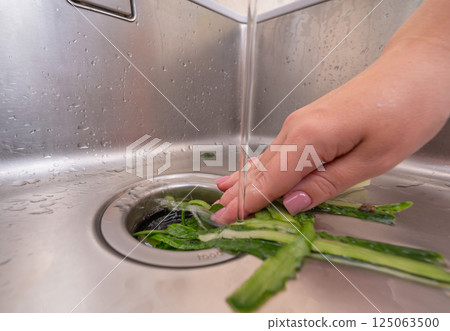 Eco-friendly kitchen cleanup: organic waste going into a sink disposal unit 125063500