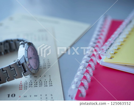 A calendar, a notebook and a watch on the table 125063552