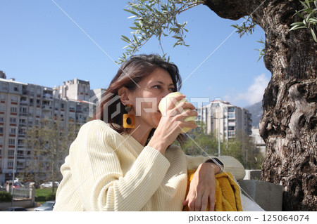 an adult woman on terrace making notes, working with phone an adult woman on terrace making notes, working with phone 125064074