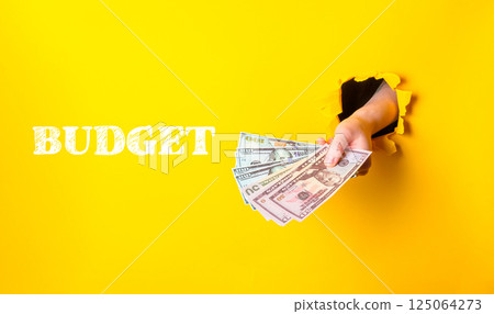 Hand holding a stack of money with the word budget written underneath 125064273