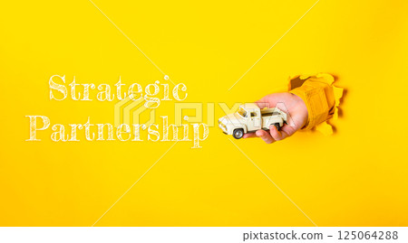 Hand holding a toy truck with the words strategic partnership written below it Hand holding a toy truck with the words strategic partnership written below it 125064288