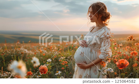 Woman is standing in a field of flowers, with a baby bump 125064582