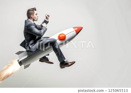 Man is sitting in a rocket, with his arms raised in the air 125065513