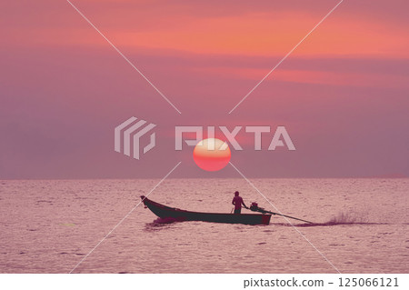 Tropical seascape is a classic traditional Thai Longtail boat set against the backdrop of a sunset orange big sun purple red sunset. Sea cruise, fishing and excursions In Thailand, travel experiences. 125066121