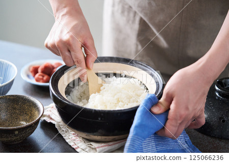 一名婦女正在鬆動陶罐裡煮好的米飯 125066236