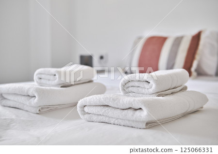Close up of freshly folded white towels placed on neatly made bed 125066331