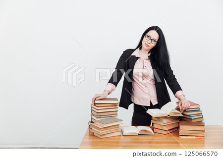 business woman teacher and stacks of educational books on table 125066570
