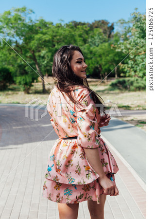 women in a summer dress with flowers walking in a spring park 125066725