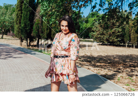 women in a summer dress with flowers walking in a spring park 125066726