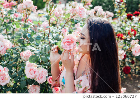 woman in summer dress inhales the aroma of spring flowers 125066727