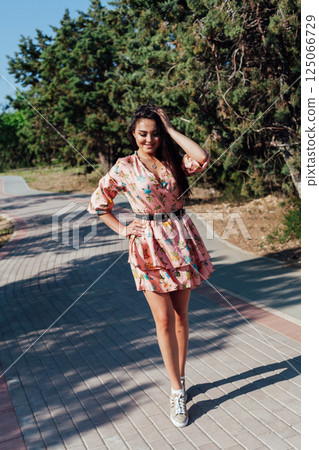 Brunette in a summer dress with flowers walking 125066729