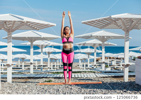 brunette does sports gymnastics yoga asana on the beach by the sea 125066736