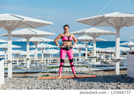 brunette does sports gymnastics yoga asana on the beach by the sea 125066737